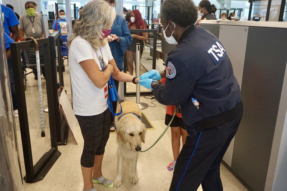 TSA Officer helps Canine Companions through the screening process. (Photo courtesy of Canine Companions South Florida)