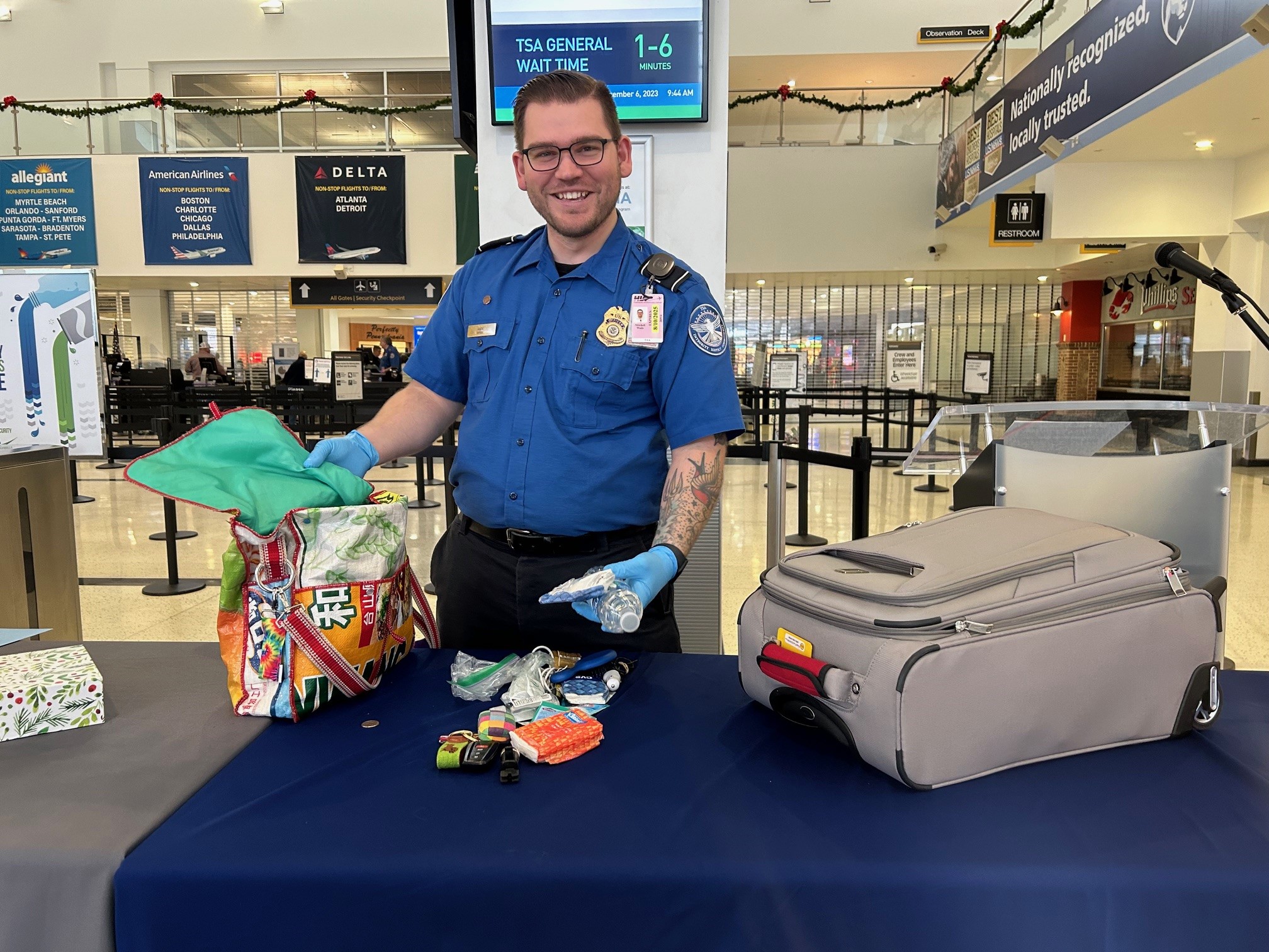 TSA officer Mitchell Wade demonstrates the importance of packing carry-on bags by starting with empty ones so that travelers know for sure that there are no prohibited items inside. (TSA photo)