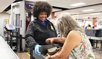 IWA TSA Officer Veda Covington helps a passenger gather her divested items . (Photo by Erica Vinegar).