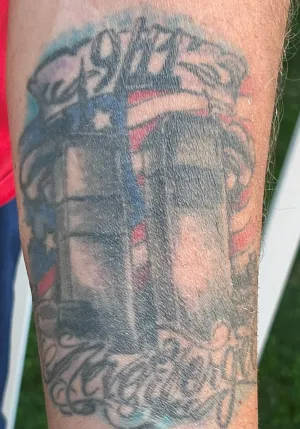 Thomas Battillo’s tattoo shows the World Trade Center towers in front of a flag with 9/11 inked above the towers and “Never Forget” below the towers. (TSA photo)